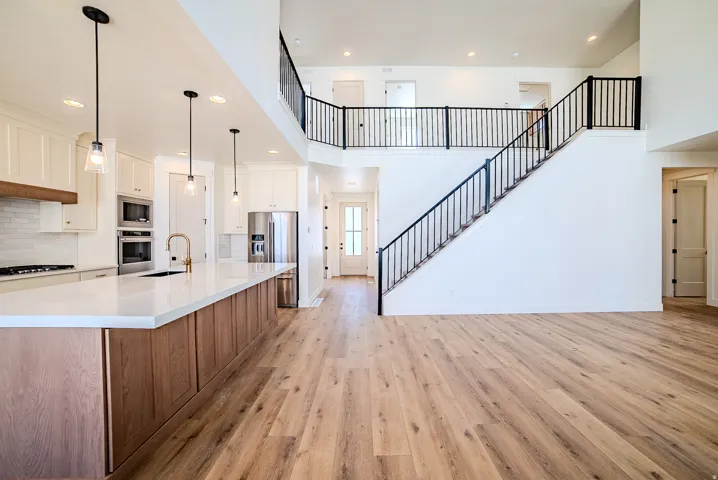 Dual tone kitchen with two tone color scheme, a spacious island, light wood finished floors, backsplash, and stainless steel appliances