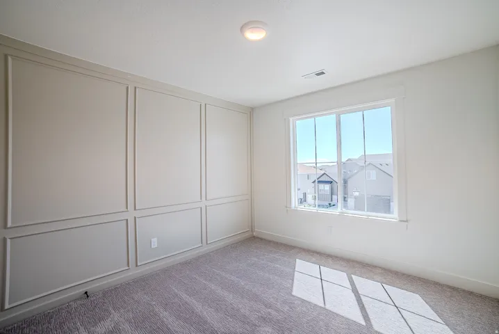 Empty room featuring light colored carpet and a decorative wall