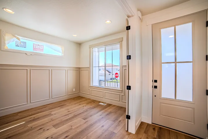 Doorway to outside featuring a decorative wall, wood-type flooring, recessed lighting, and wainscoting
