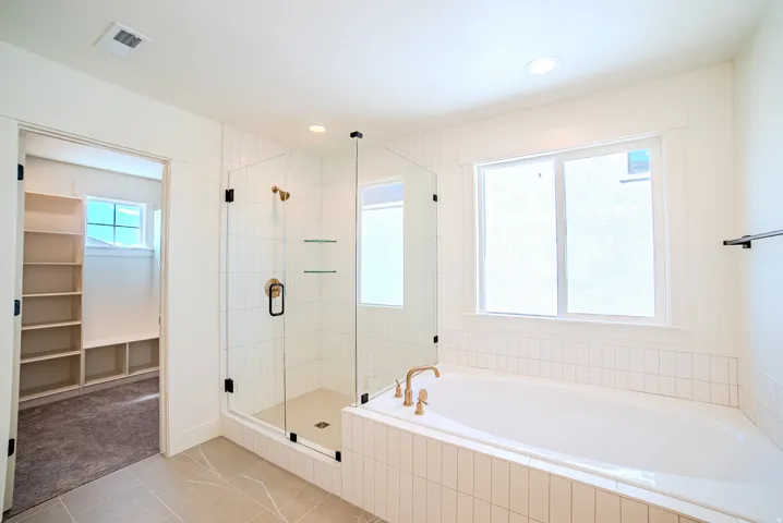 Bathroom featuring a stall shower, a bath, light tile patterned flooring, a spacious closet, and recessed lighting