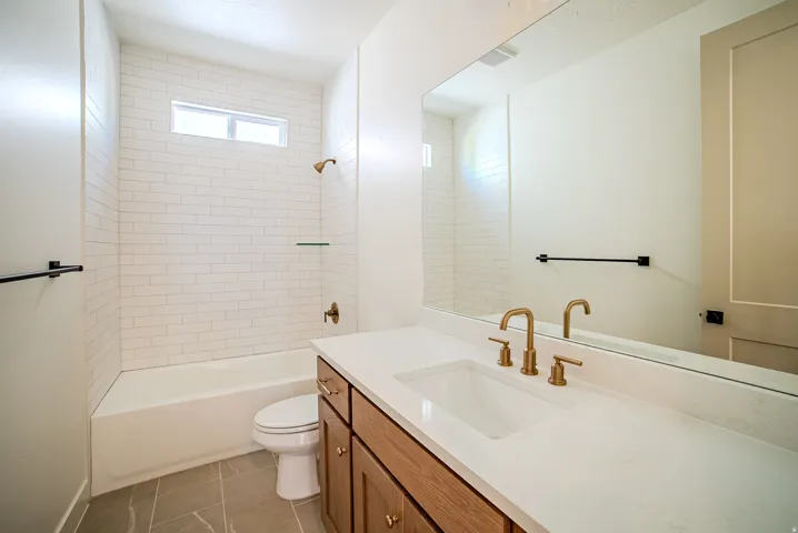 Full bath with vanity, bathtub / shower combination, and dark tile patterned flooring