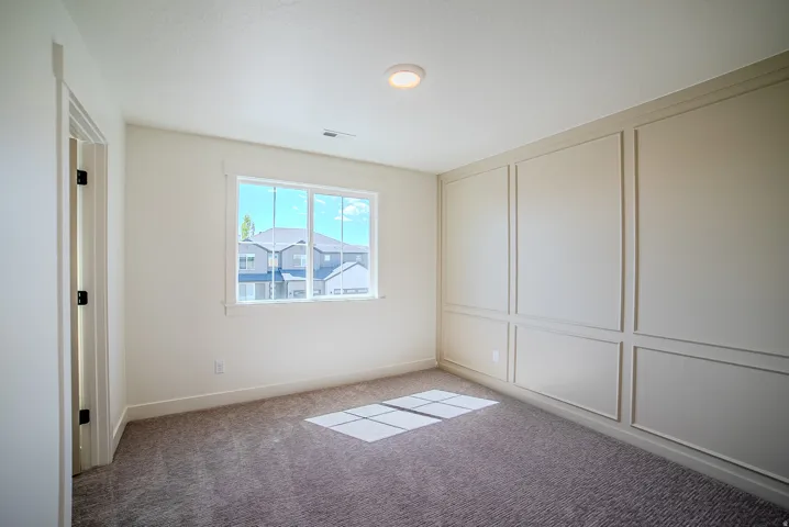 Unfurnished bedroom featuring a decorative wall and light carpet