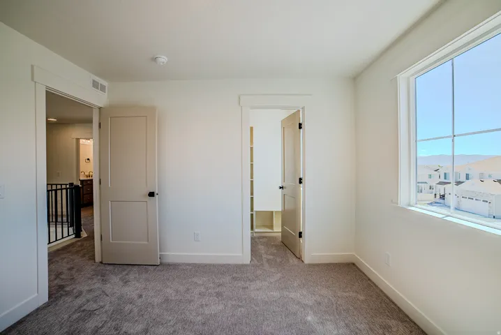 Unfurnished bedroom with light colored carpet and baseboards