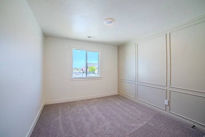 Spare room with a decorative wall, carpet flooring, and a textured ceiling