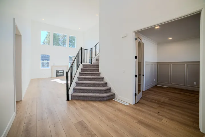 Stairs featuring a glass covered fireplace, recessed lighting, hardwood / wood-style flooring, a high ceiling, and a wainscoted wall