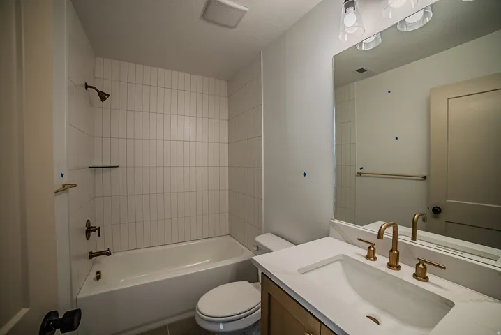Bathroom with vanity, tub / shower combination, and a textured ceiling
