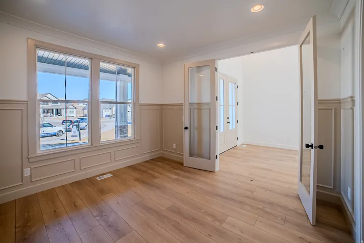 Empty room featuring wainscoting, a decorative wall, light wood-style flooring, and recessed lighting