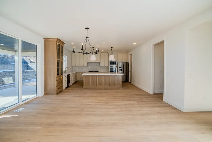 Kitchen with suspended lighting, a kitchen island, light wood-style flooring, stainless steel appliances, and glass insert cabinets