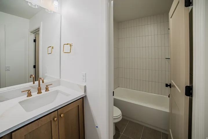Full bath featuring vanity, shower / washtub combination, and dark tile patterned floors