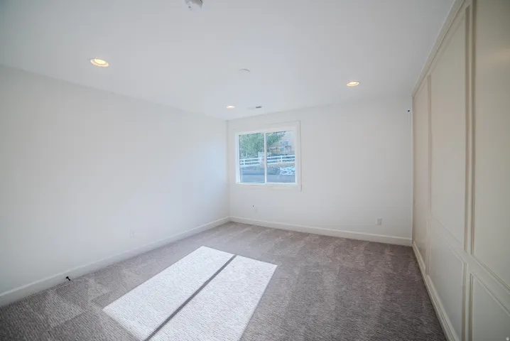 Empty room with light carpet and recessed lighting