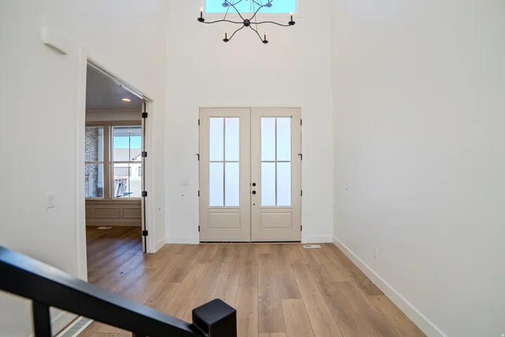 Foyer featuring french doors, light wood-style floors, plenty of natural light, a high ceiling, and suspended lighting