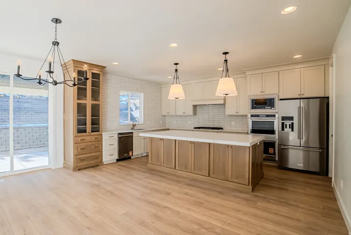 Kitchen with stainless steel appliances, a center island, dual tone cabinets, glass fronted cabinets, and backsplash