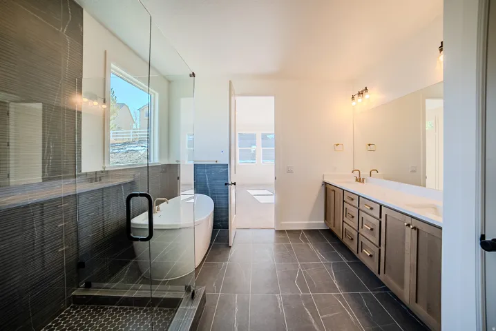 Full bath featuring double vanity, a freestanding bath, a shower stall, and tile walls
