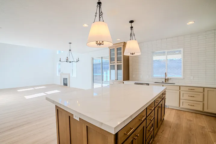 Kitchen with dual tone cabinets, a kitchen island, backsplash, a glass covered fireplace, and light wood-style flooring