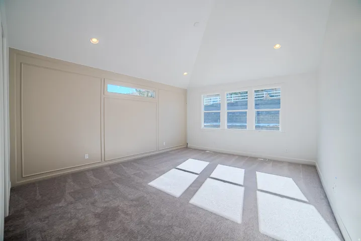 Spare room with light colored carpet, a decorative wall, recessed lighting, and vaulted ceiling
