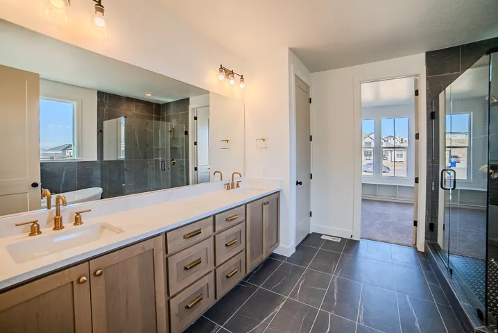 Full bathroom featuring double vanity, a stall shower, and dark tile patterned floors