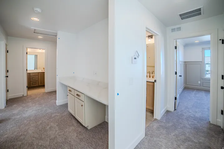 Hallway with light colored carpet and recessed lighting