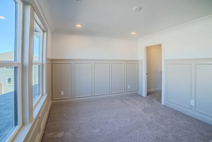 Carpeted empty room with a decorative wall, a wainscoted wall, ornamental molding, and recessed lighting