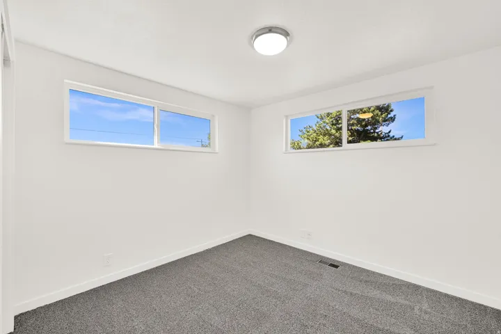 Spare room featuring baseboards and dark carpet