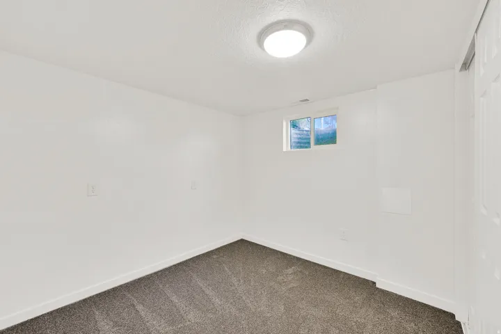 Empty room with dark colored carpet and a textured ceiling