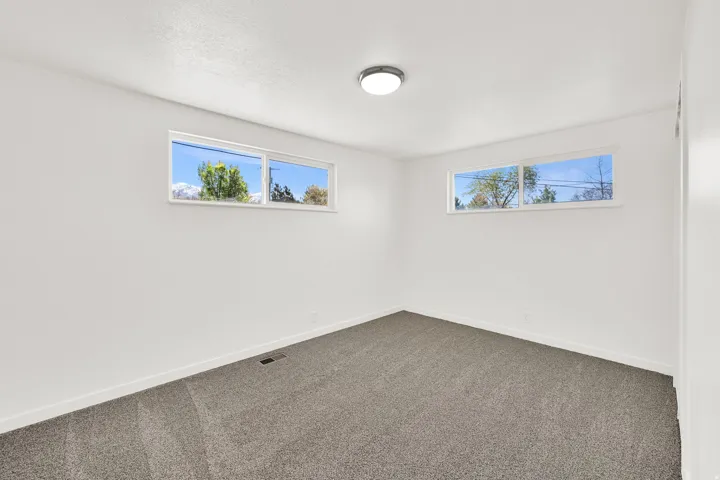 Empty room featuring dark carpet and healthy amount of natural light