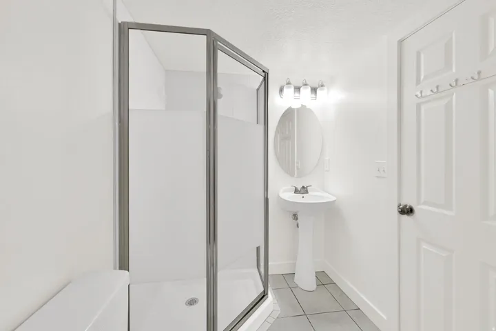 Bathroom with a textured ceiling, a stall shower, and light tile patterned flooring