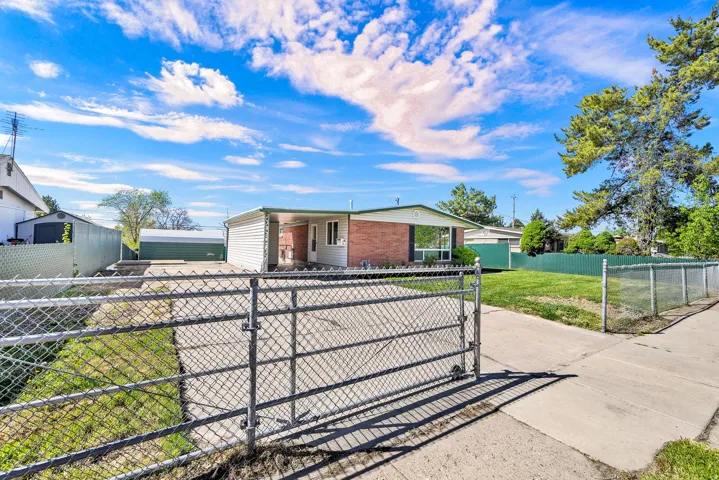 View of front of home with a fenced front yard, a gate, driveway, and brick siding