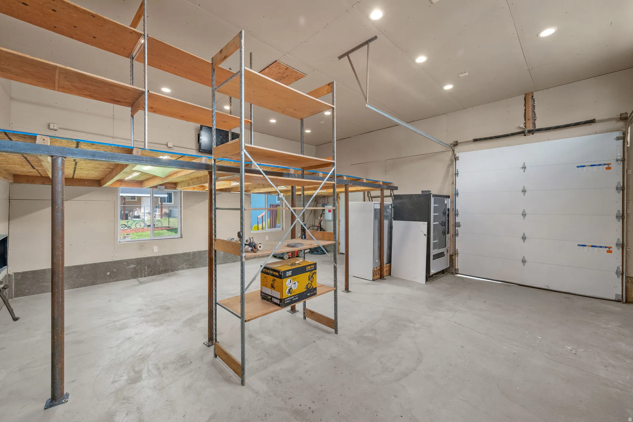 Spacious garage offering significant storage solutions with built-in shelving and an elevated platform