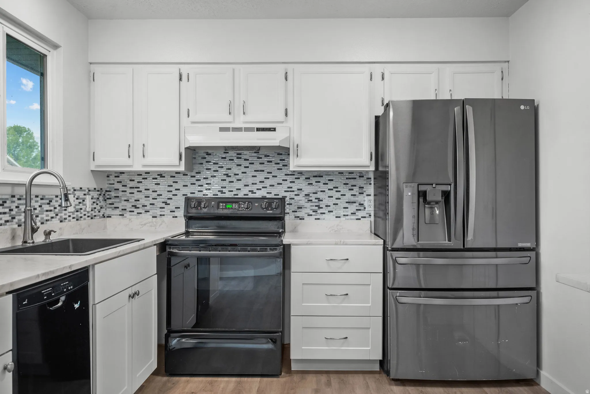 Kitchen featuring white cabinetry, light-toned countertops, and a mosaic tile backsplash