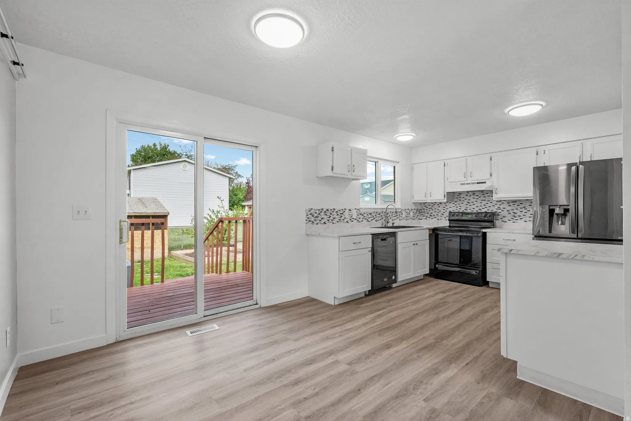 Open-concept kitchen featuring white cabinetry and light-toned countertops