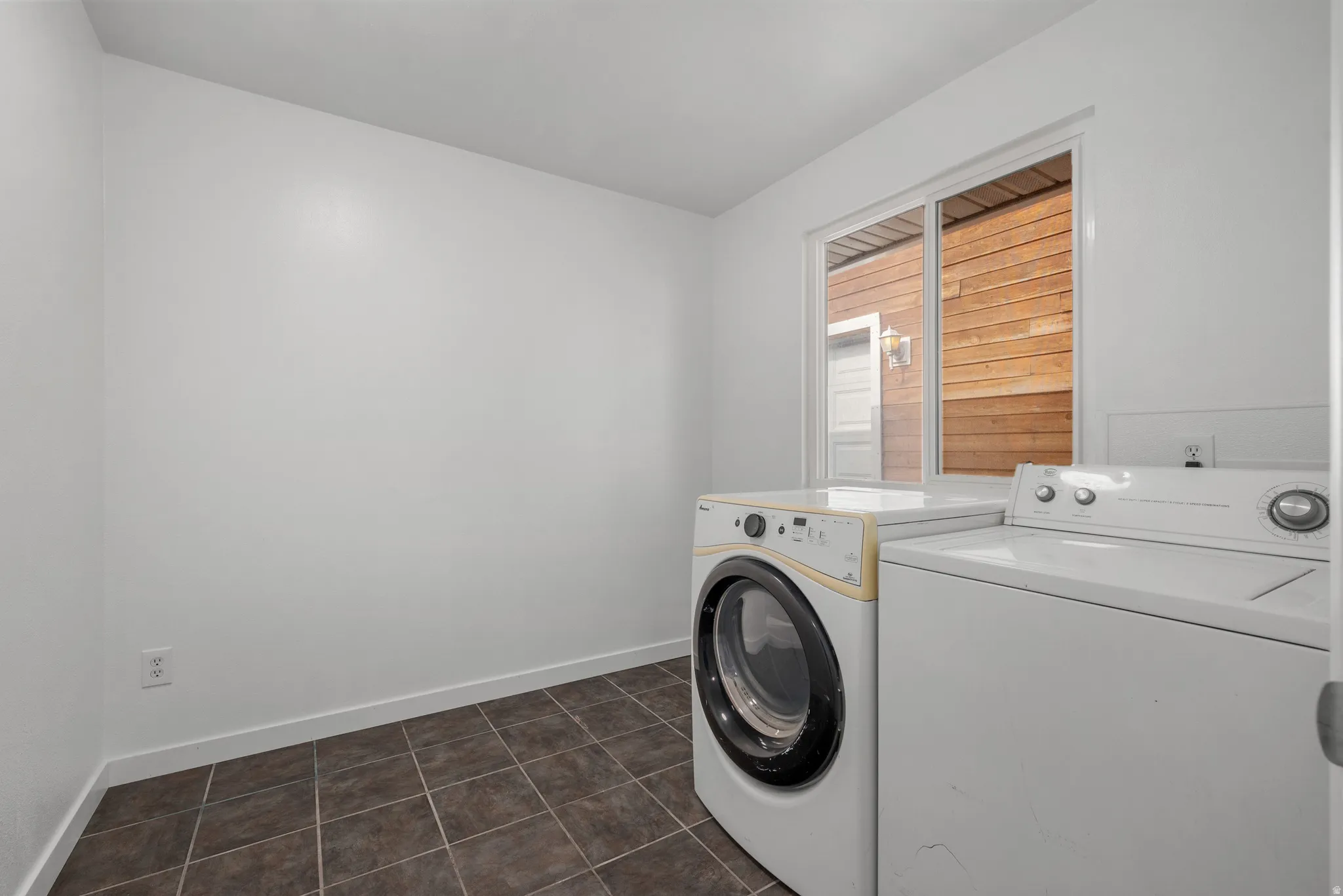 Utility area with tiled flooring, white walls, and a window providing natural light