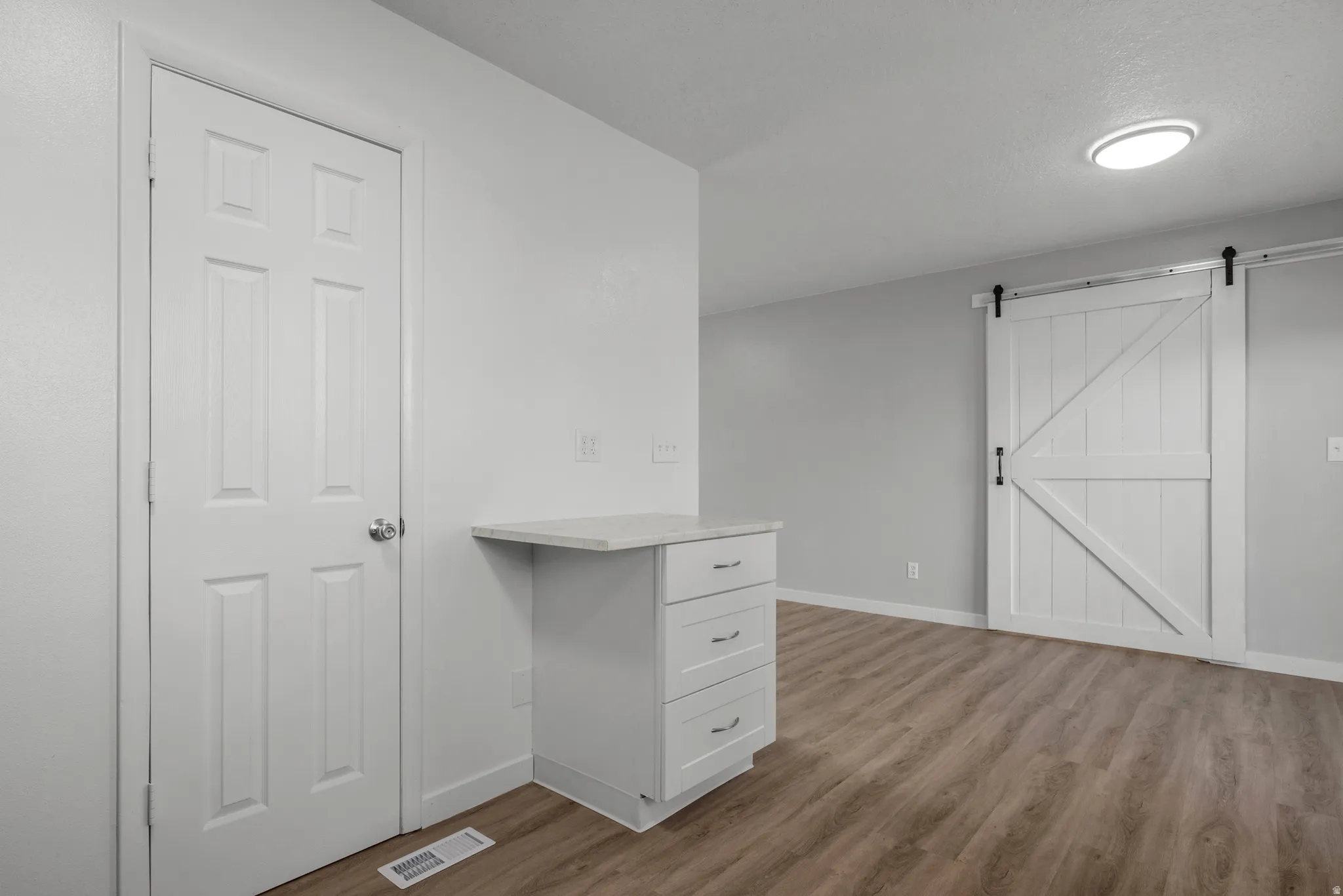 Wood-finish flooring throughout, featuring a white barn door on a black track system