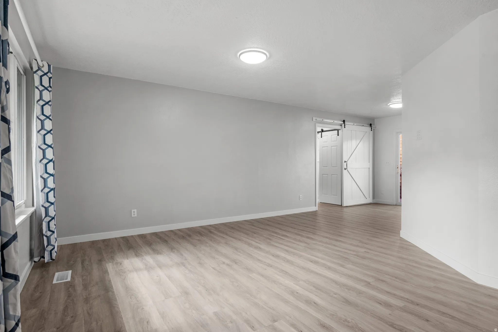 Spacious interior featuring wide-plank wood-finish flooring and light gray wall tones