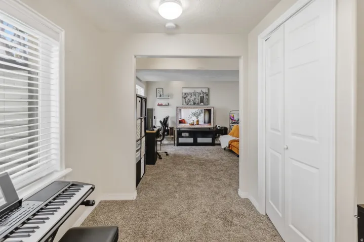 Hall featuring light carpet and a textured ceiling
