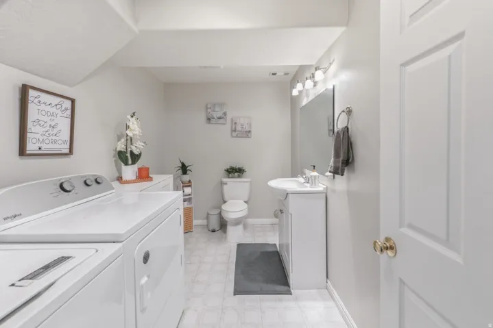 Bathroom featuring vanity, washing machine and clothes dryer, and light floors