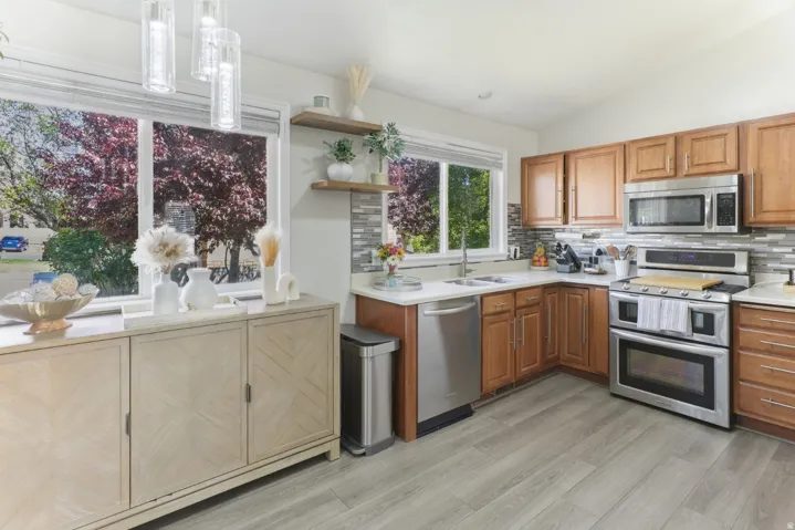 Kitchen with stainless steel appliances, open shelves, lofted ceiling, decorative light fixtures, and decorative backsplash