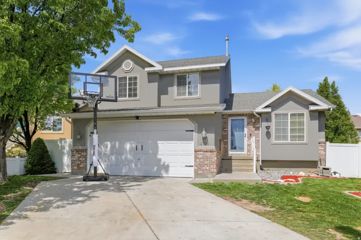 Traditional home featuring brick siding, a garage, driveway, stucco siding, and roof with shingles