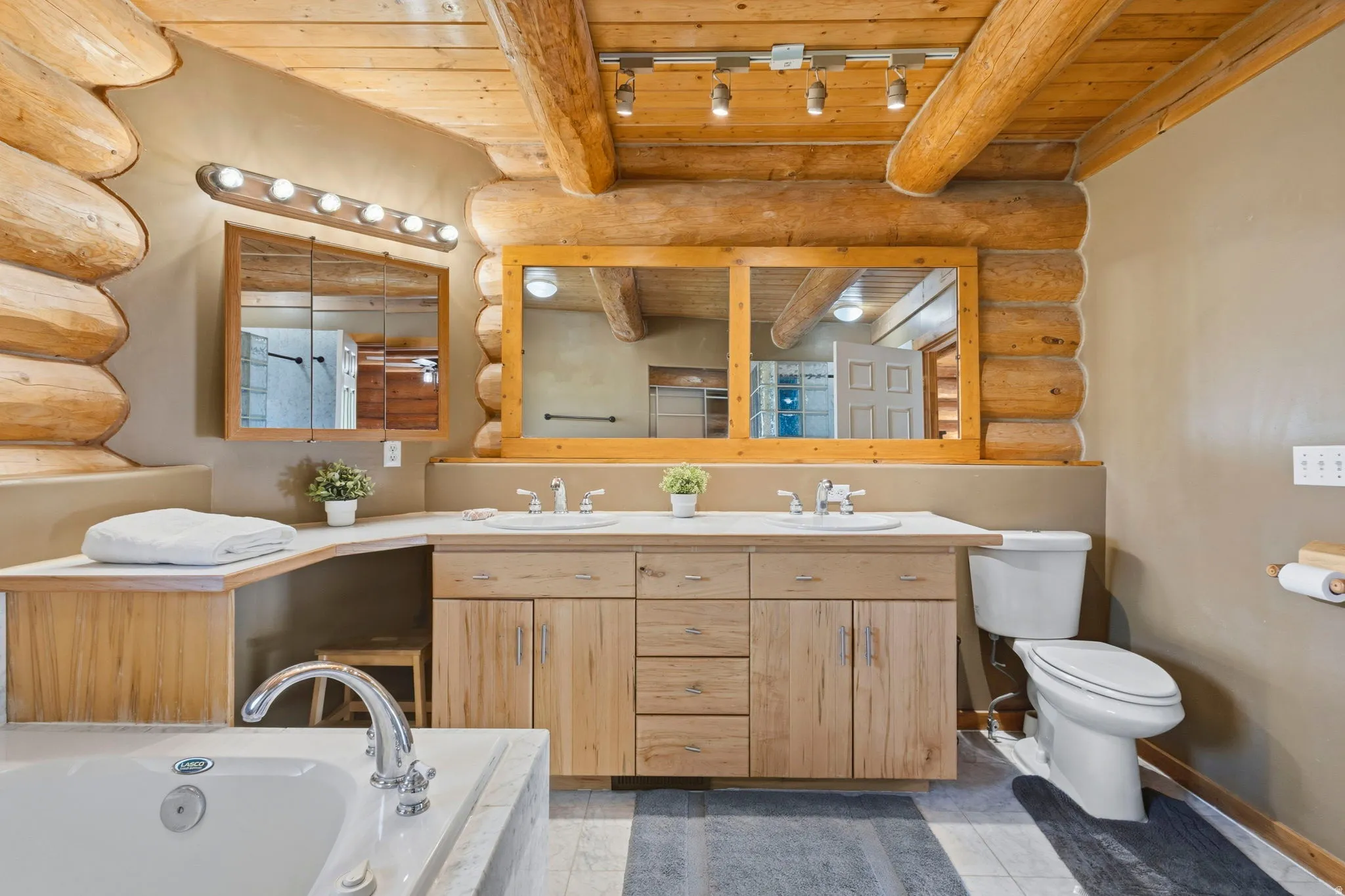 Bathroom featuring log walls, a wooden ceiling with exposed beams, double vanity, a bath, and light tile patterned flooring