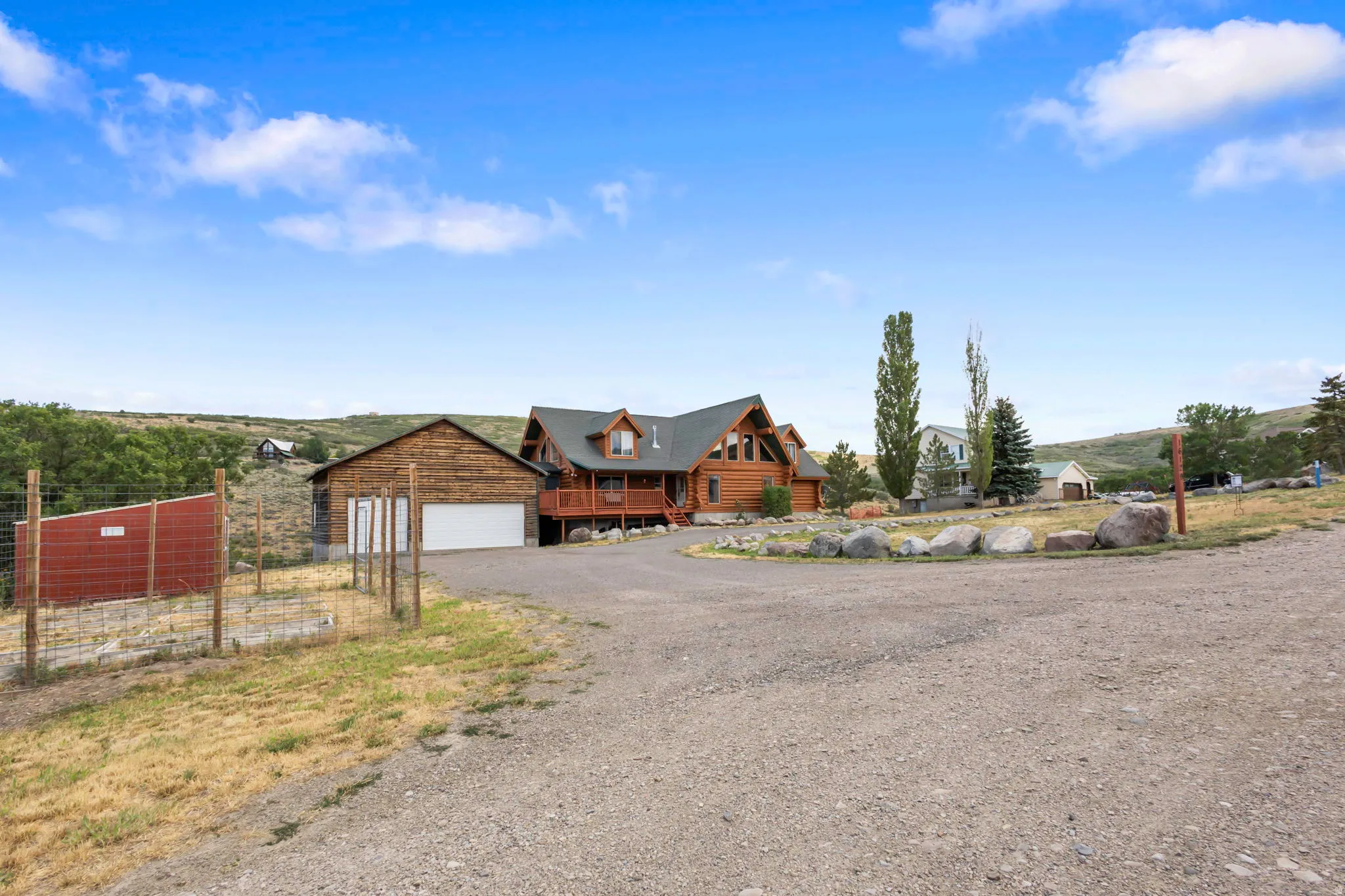 Rustic log home featuring a multi-level deck, dark gabled roof, and multiple dormer windows