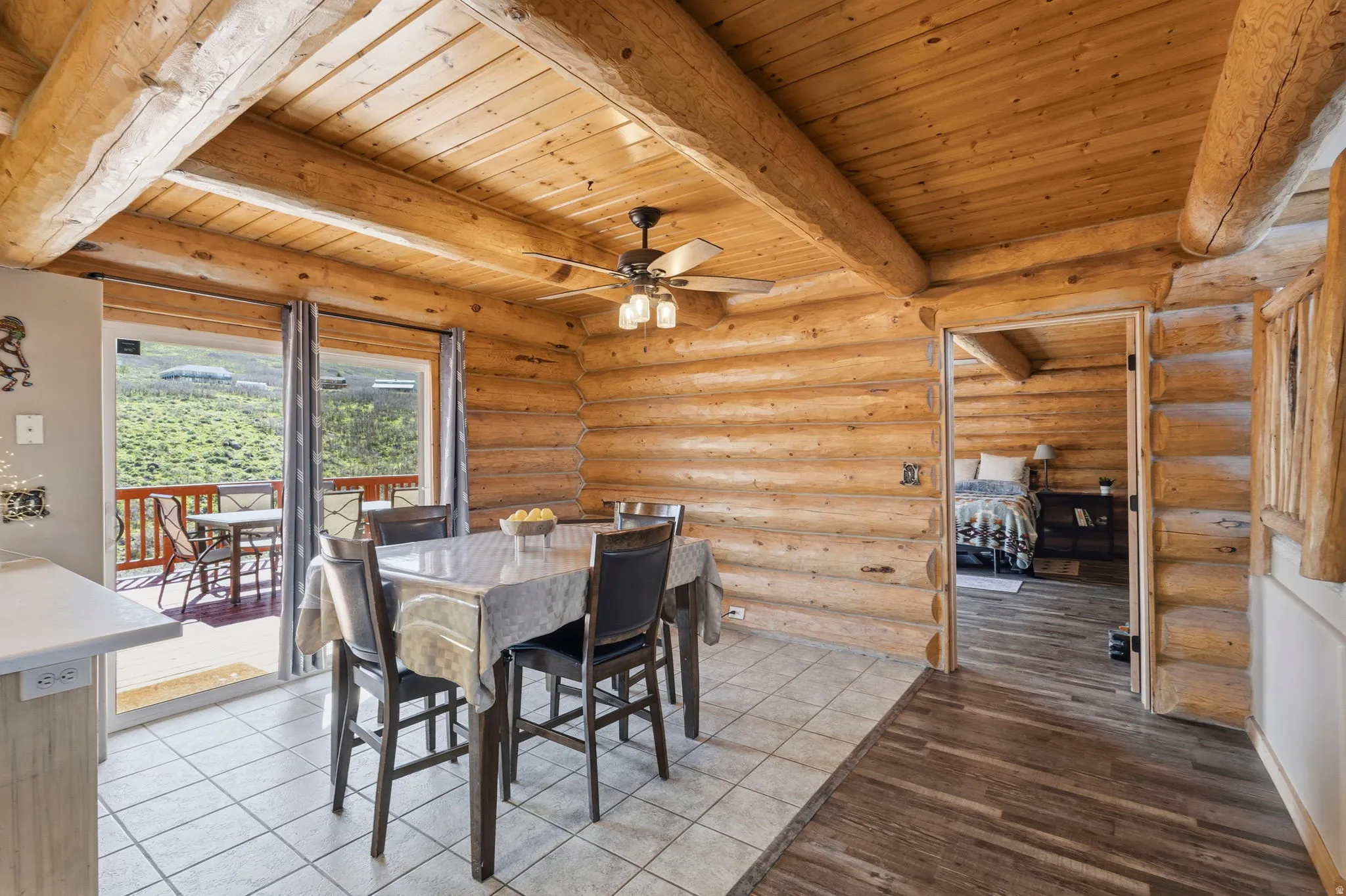 Dining area with a wooden ceiling with exposed beams, a ceiling fan, rustic walls, and wood finished floors