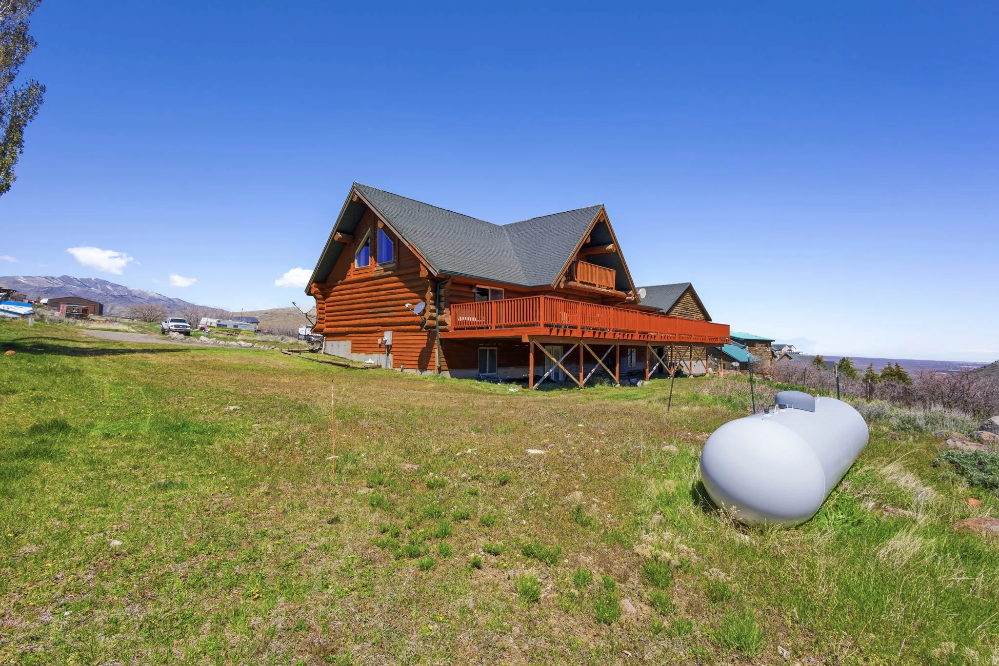 View of home's exterior featuring a deck with mountain view, log exterior, and a yard