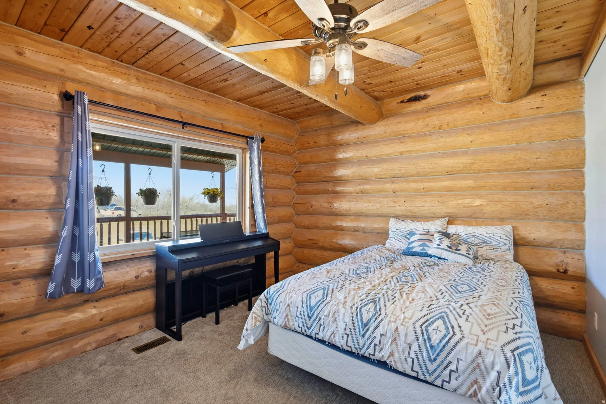 Bedroom with carpet, rustic walls, ceiling fan, and a wooden ceiling with exposed beams