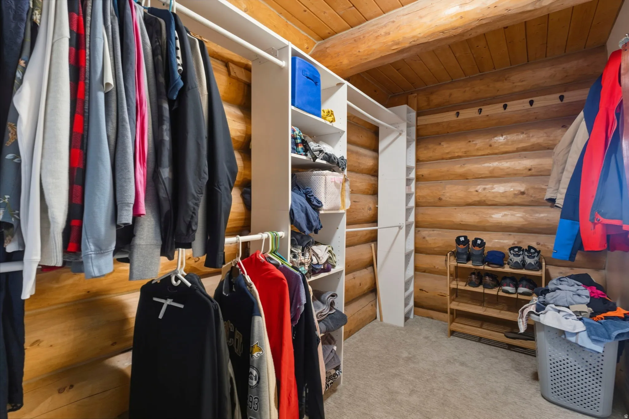 Walk in closet with beam ceiling and light carpet