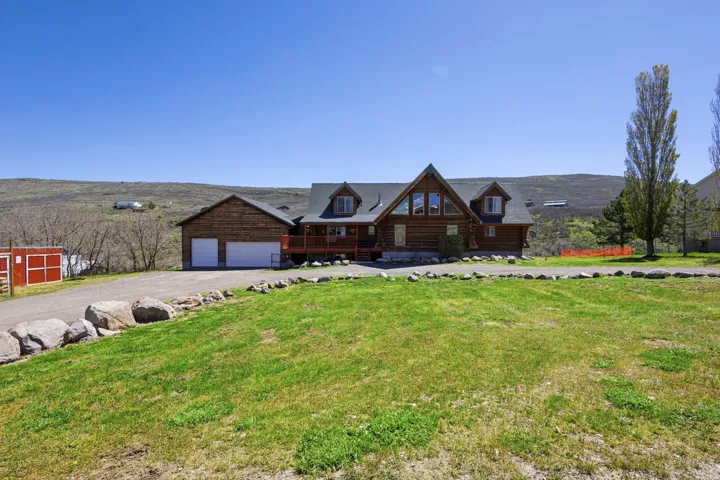 Log home with a mountain view, a porch, a front yard, and driveway