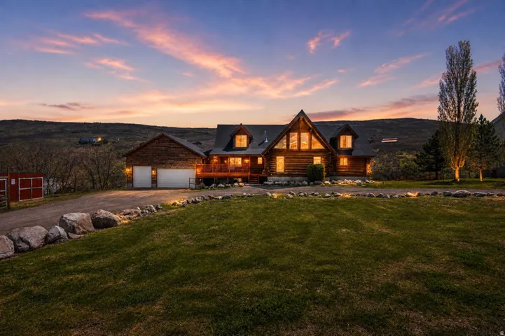 Log-style house featuring covered porch, a mountain view, driveway, a lawn, and log siding