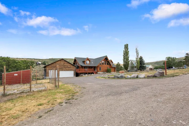 Rustic log home featuring a multi-level deck, dark gabled roof, and multiple dormer windows