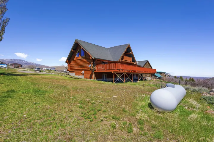 View of home's exterior featuring a deck with mountain view, log exterior, and a yard