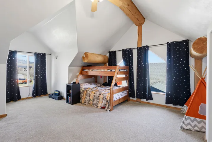 Bedroom with light carpet and beam ceiling