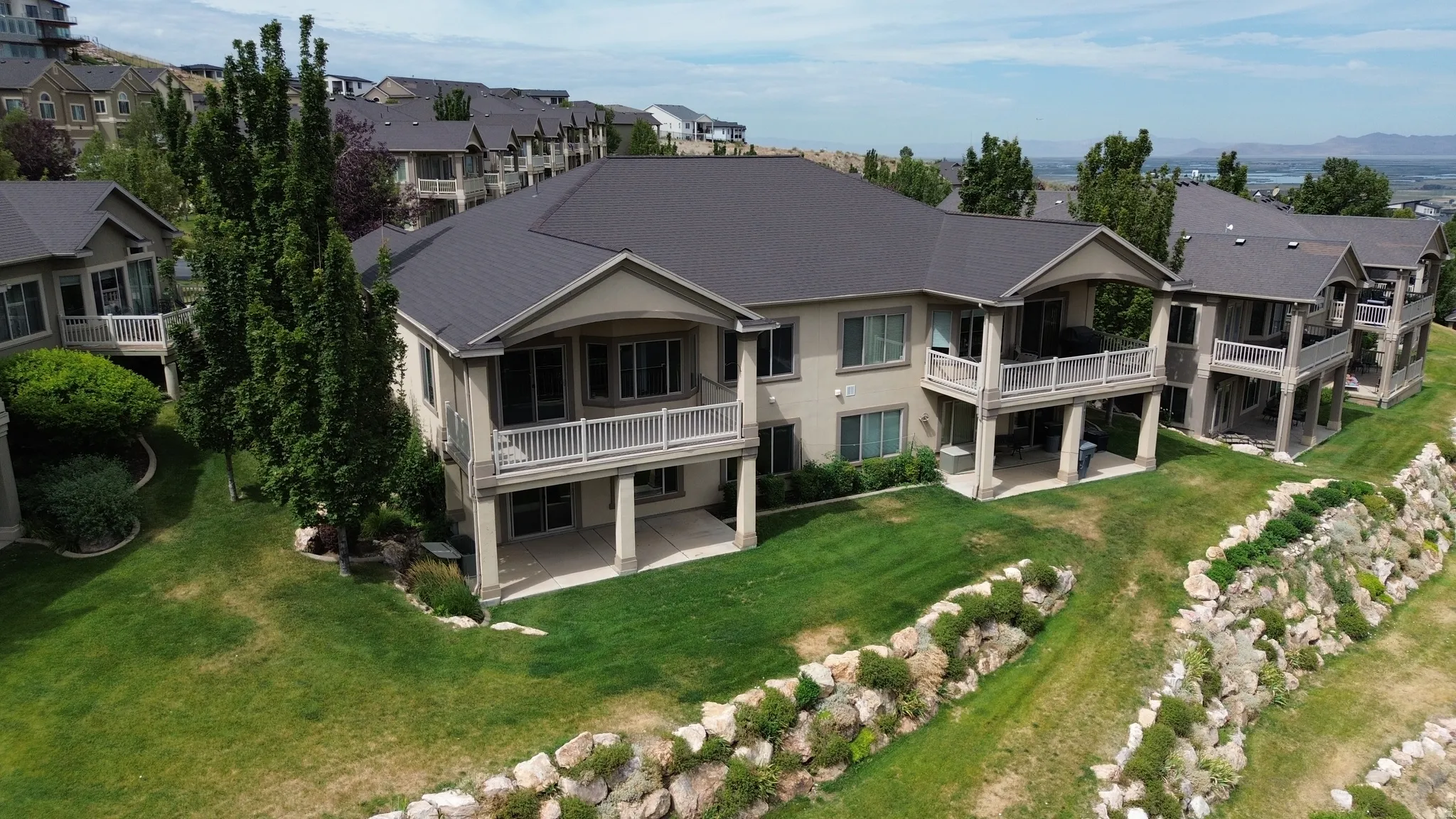 Contemporary residence featuring a dark gray roof, light-colored stucco exterior, and multiple balconies with white railings