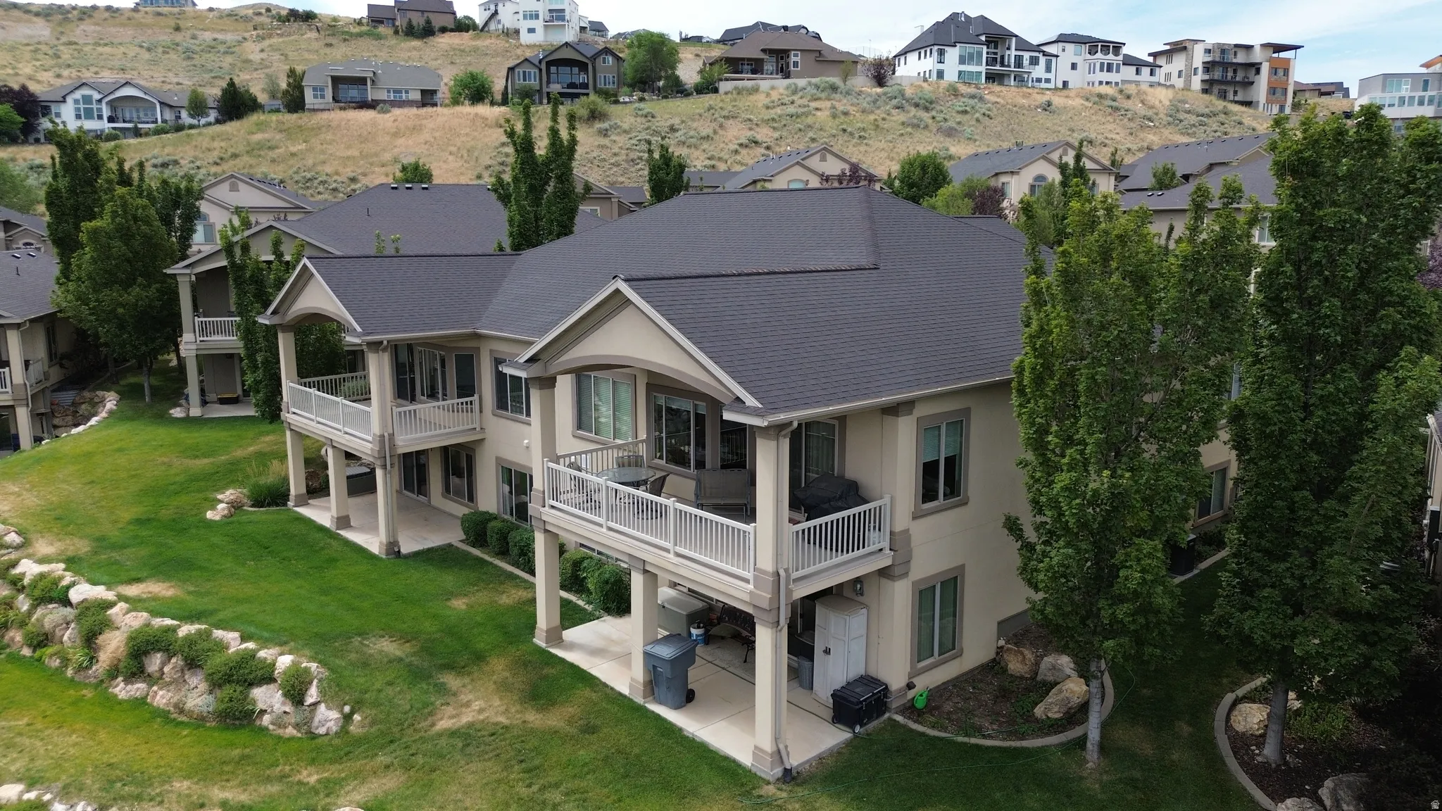 Multi-level residence featuring balconies, patios, and a manicured lawn